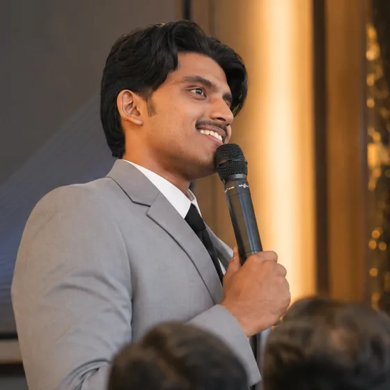 Jonah Joy smiling as he speaks to a room with a microphone